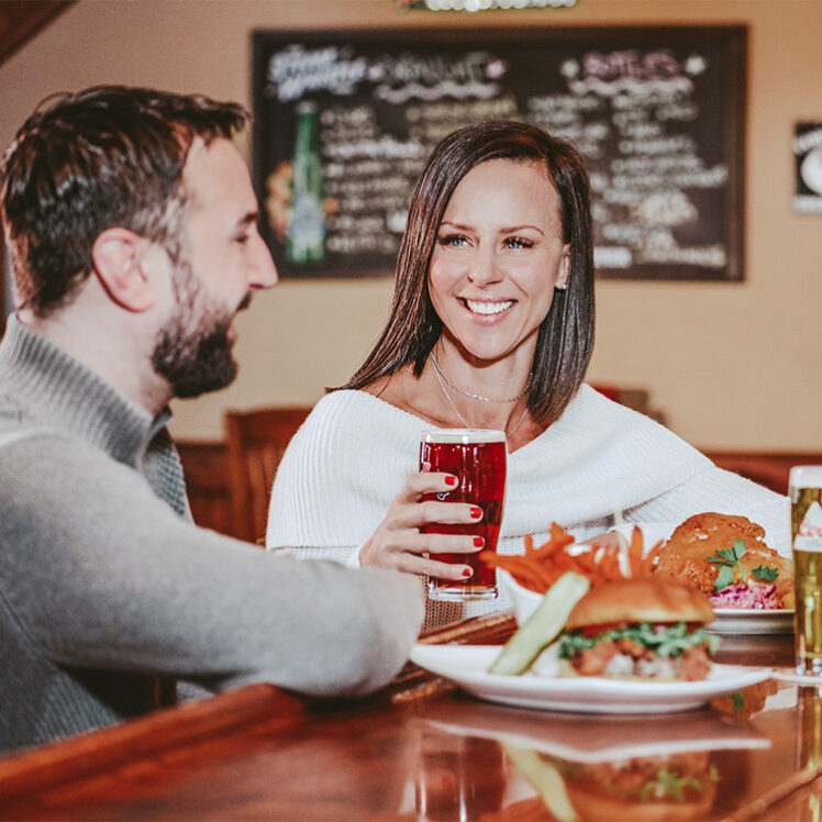 A couple enjoying comfort foods from Jordan House Tavern, minutes from Inn On The Twenty