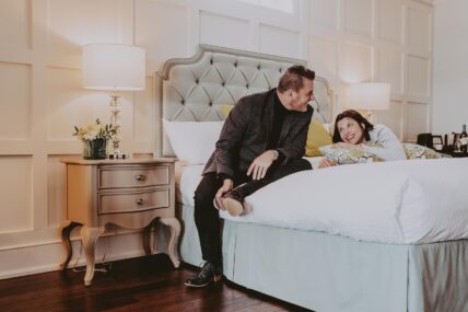A couple relaxing in their guest room at the Queen’s Landing hotel.